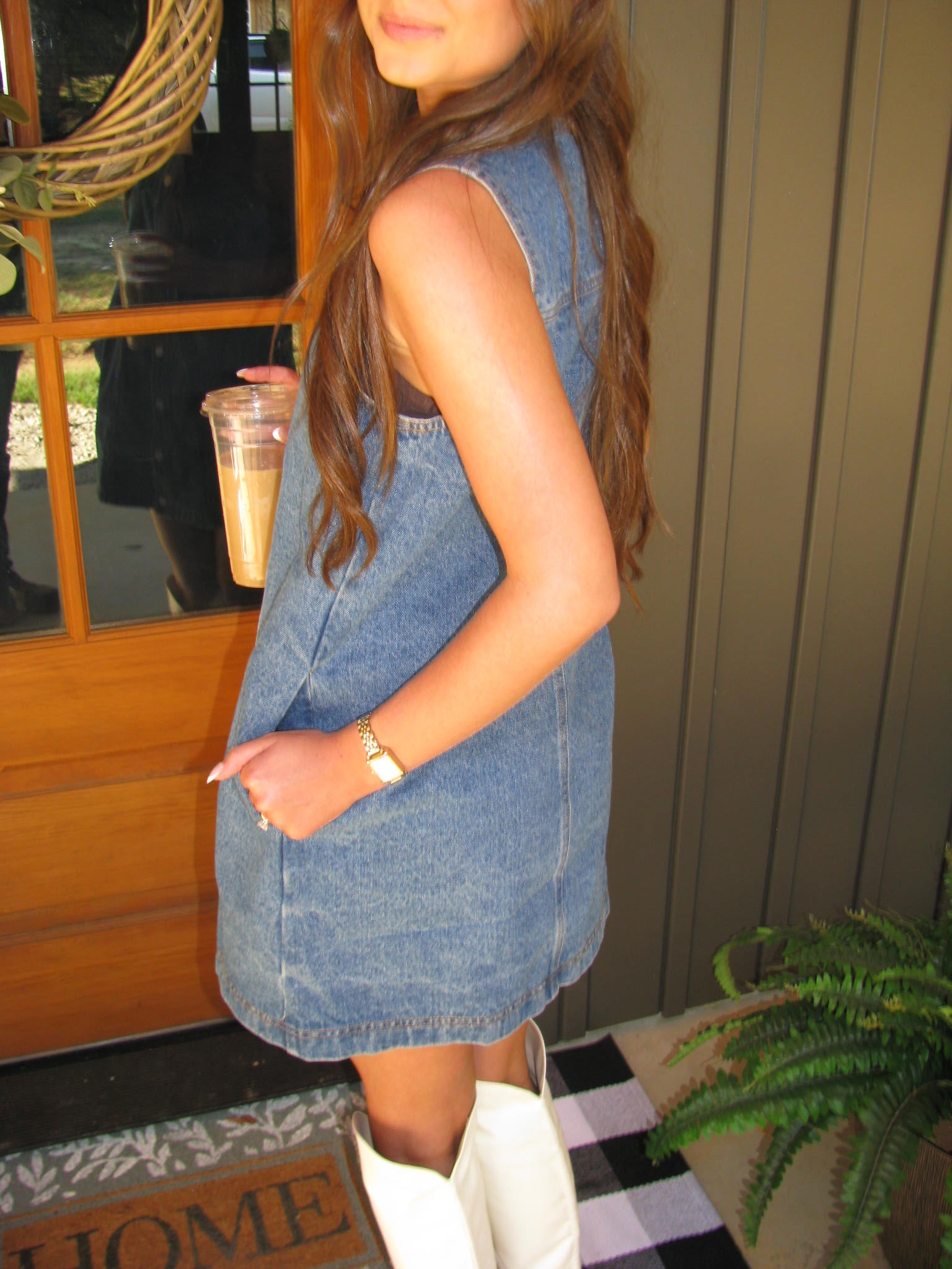 Person wearing a denim skirt sitting on a wooden stool outdoors.