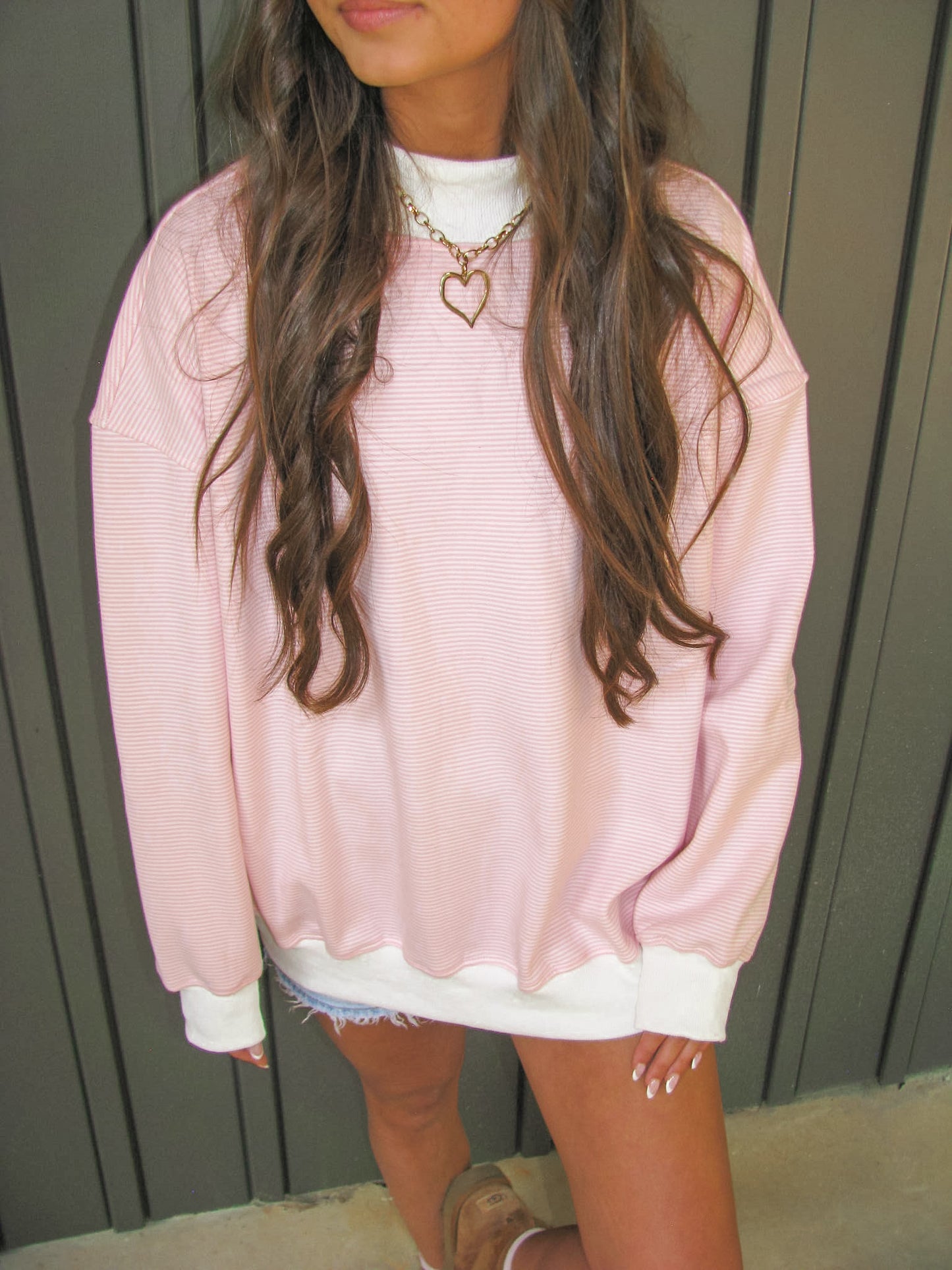 Person wearing a pink stripe oversized mock neck sweater with a neutral background