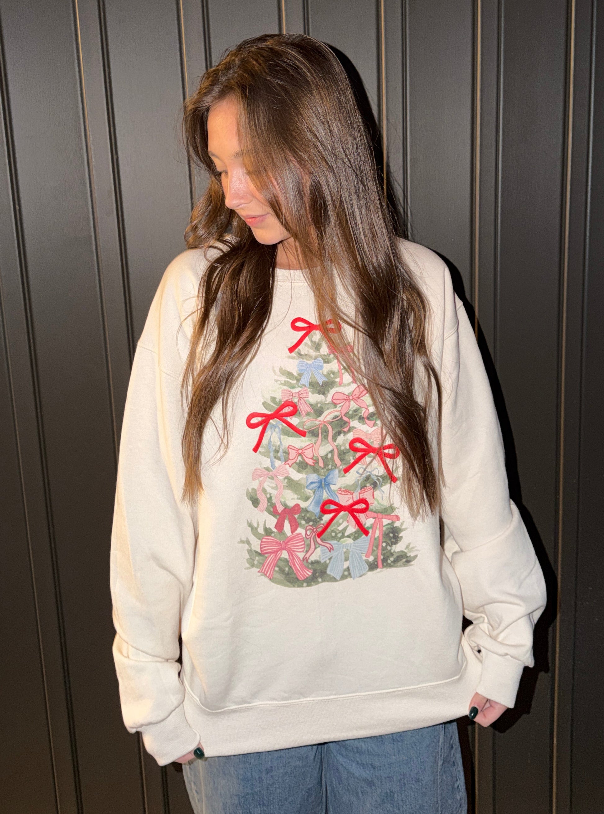 Person wearing a white sweatshirt with Christmas designs and bows
