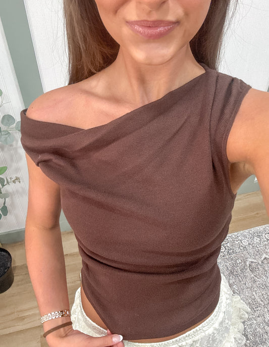 woman showing off brown asymmetrical knit sweater. 