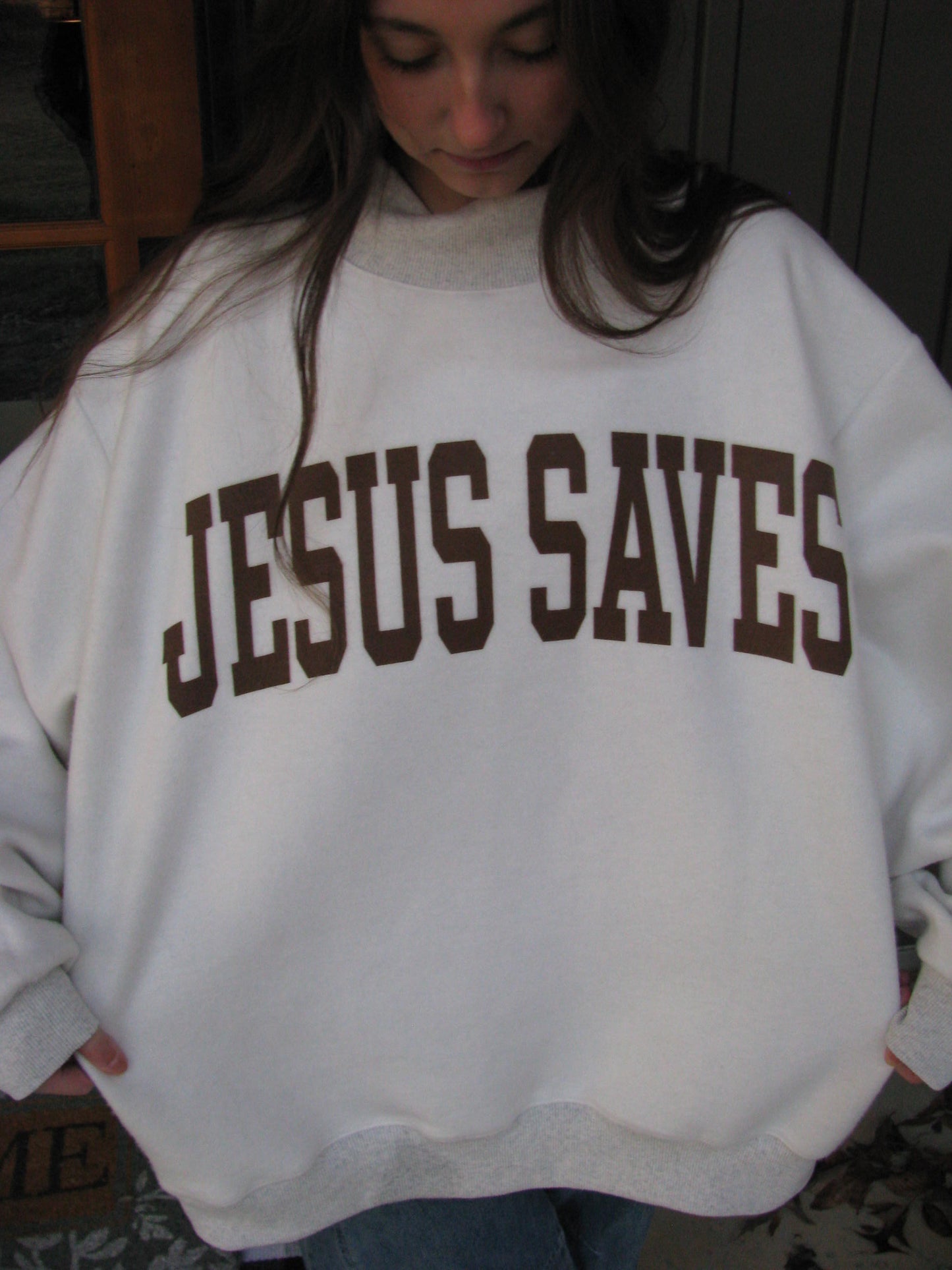 Person wearing a white hoodie with 'JESUS SAVES' printed in brown.